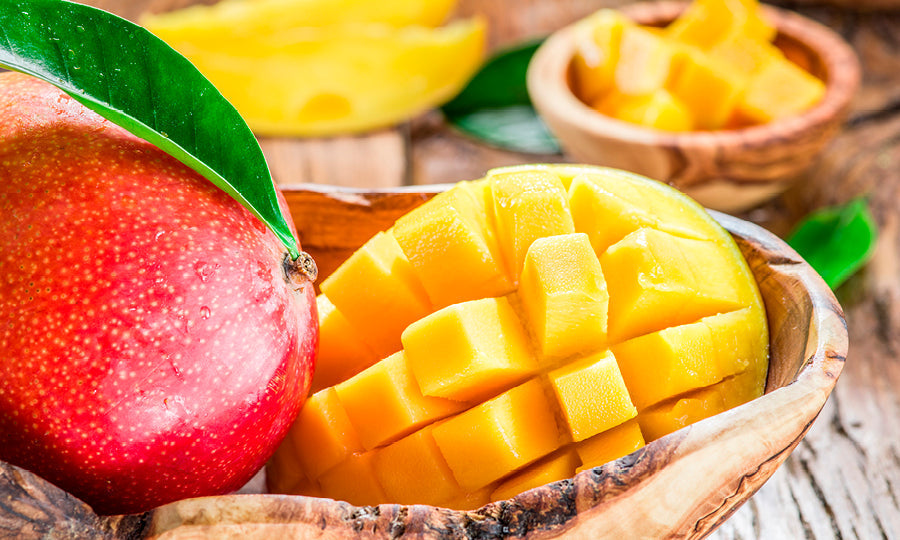 Whole and cut mango fruit displayed in wooden bowls.