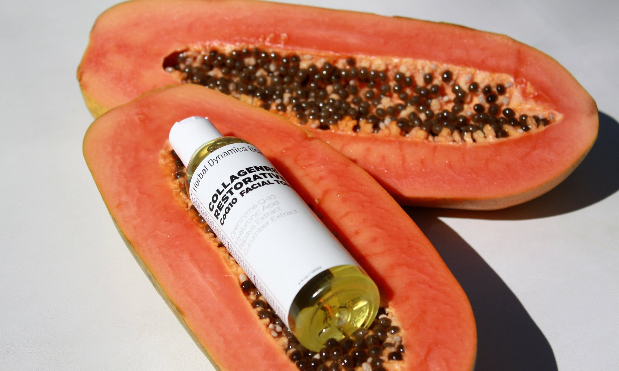 CollagenR8 CoQ10 facial toner bottle resting on sliced papaya